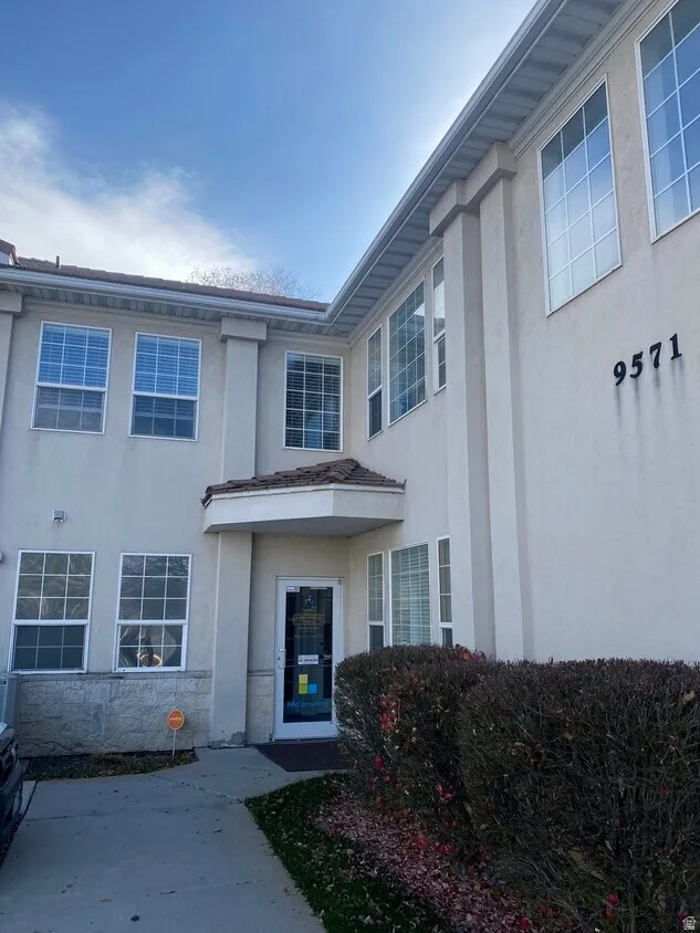 Stucco exterior featuring multiple large windows and a covered entrance