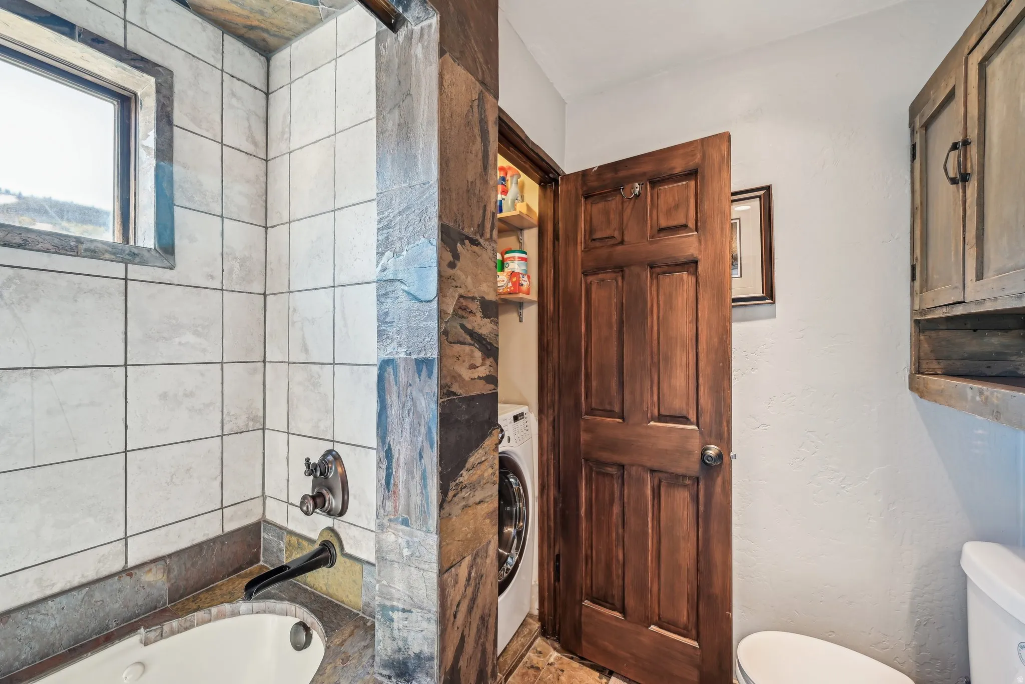 Bathroom featuring a bath, a textured wall, washer / dryer, and a shower
