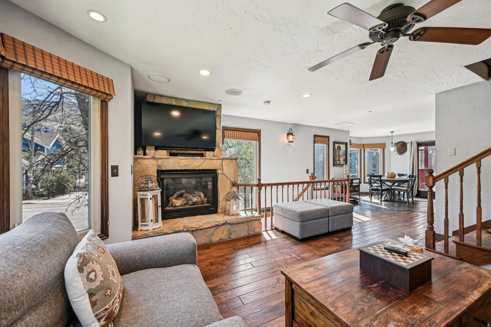 Living area with a stone fireplace, hardwood / wood-style floors, recessed lighting, and ceiling fan