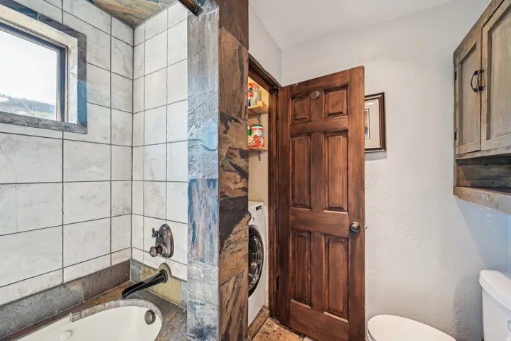 Bathroom featuring a bath, a textured wall, washer / dryer, and a shower