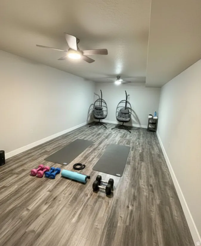 Spacious room featuring wood-finish flooring and two ceiling fans with integrated lighting