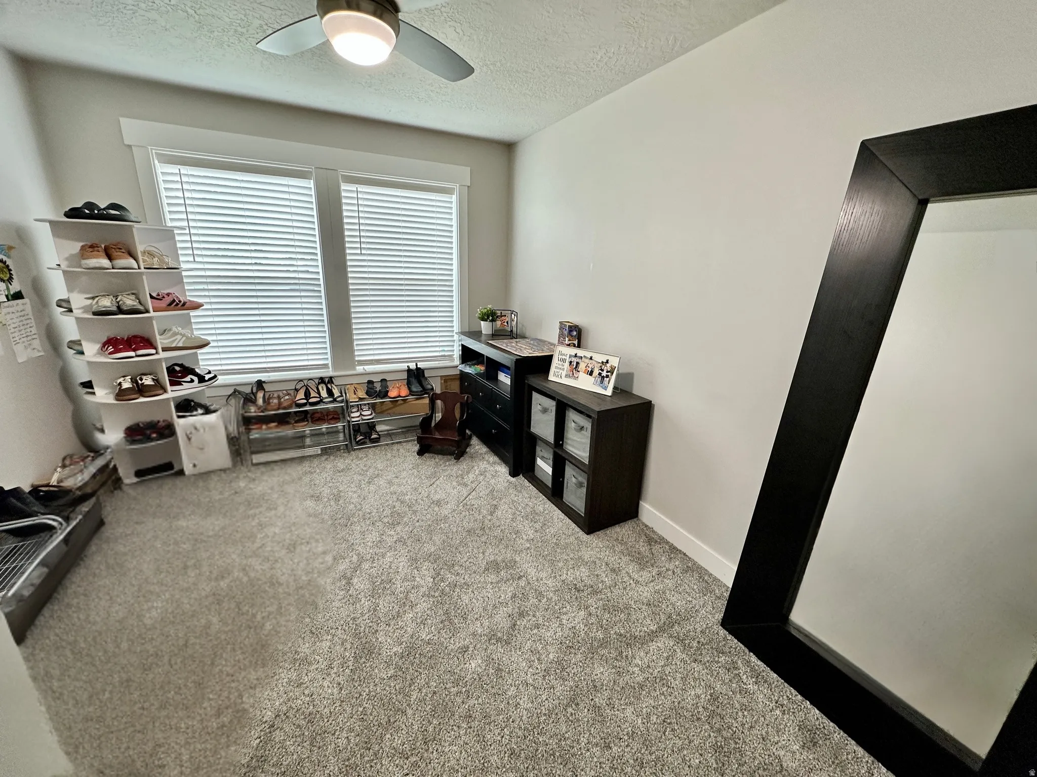 Bright interior space featuring light gray carpeting and a ceiling fan with integrated lighting