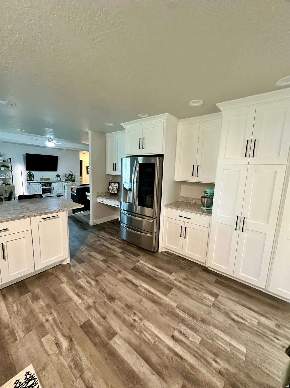 Kitchen featuring white shaker-style cabinetry, stainless steel appliances, granite-finish countertops, and wood-finish flooring