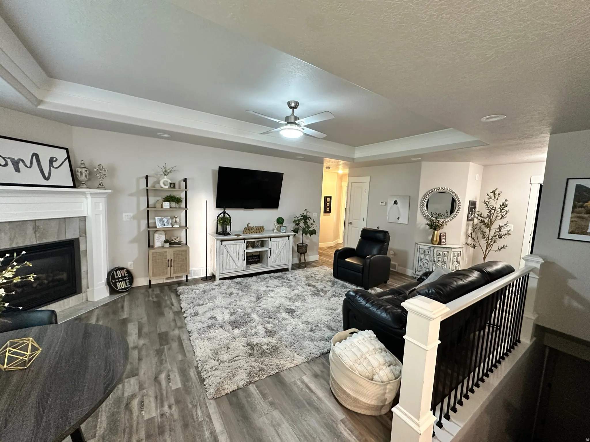 Open-concept living space featuring wood-finish flooring, a tray ceiling with recessed lighting, and a contemporary ceiling fan