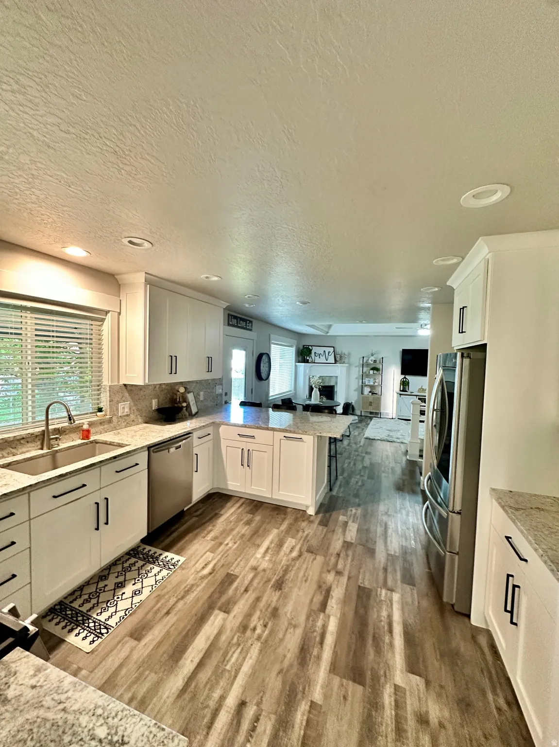 Kitchen featuring white cabinetry, light-toned countertops, stainless steel appliances, and wood-finish flooring
