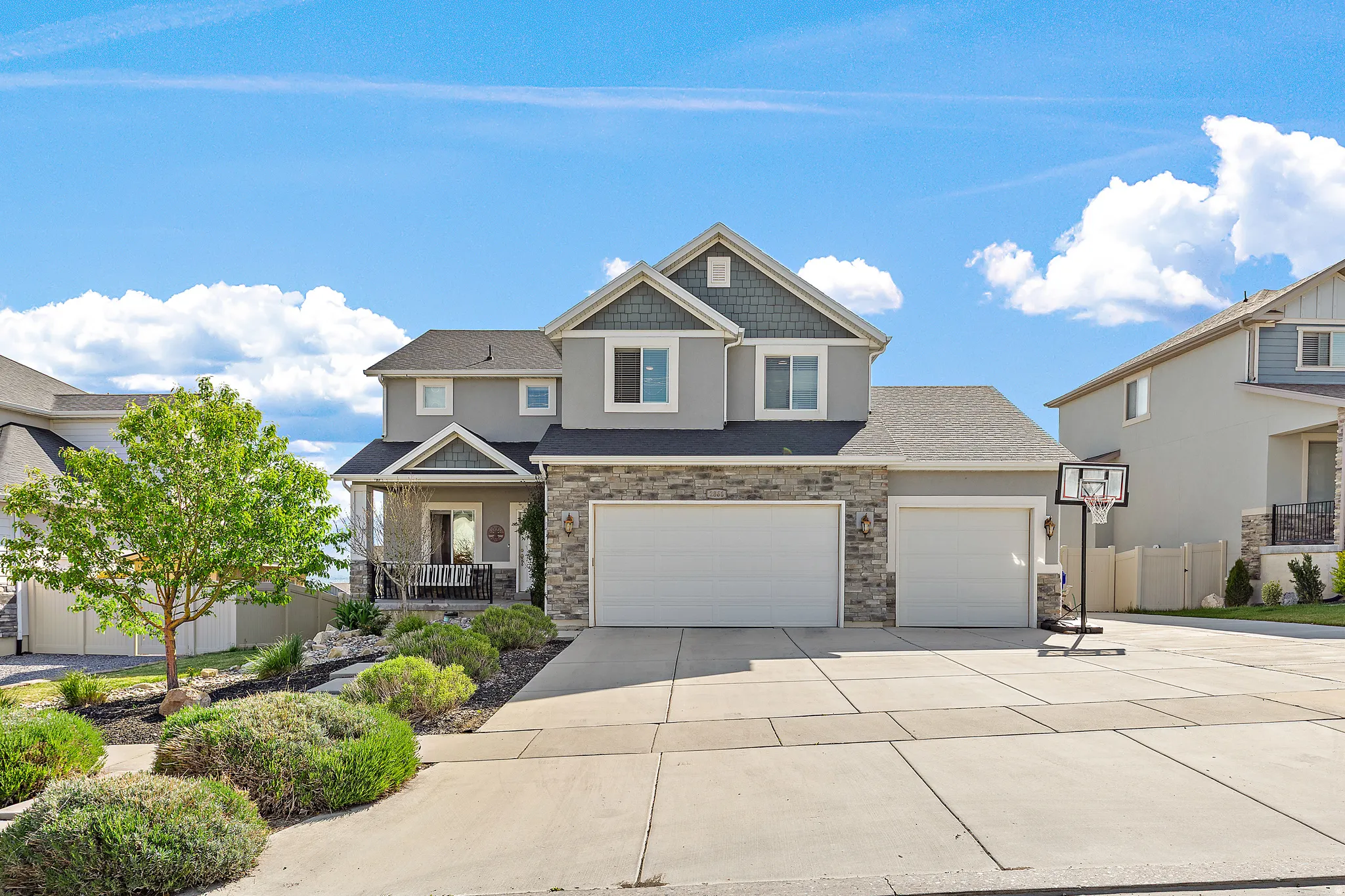 Contemporary two-story residence featuring a stone and siding exterior, an attached two-car garage, and a covered front porch