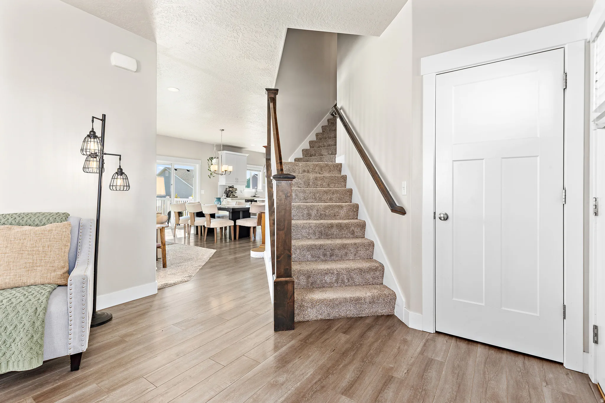 Entryway featuring wood-finish flooring and a carpeted staircase with dark wood newel post and handrail