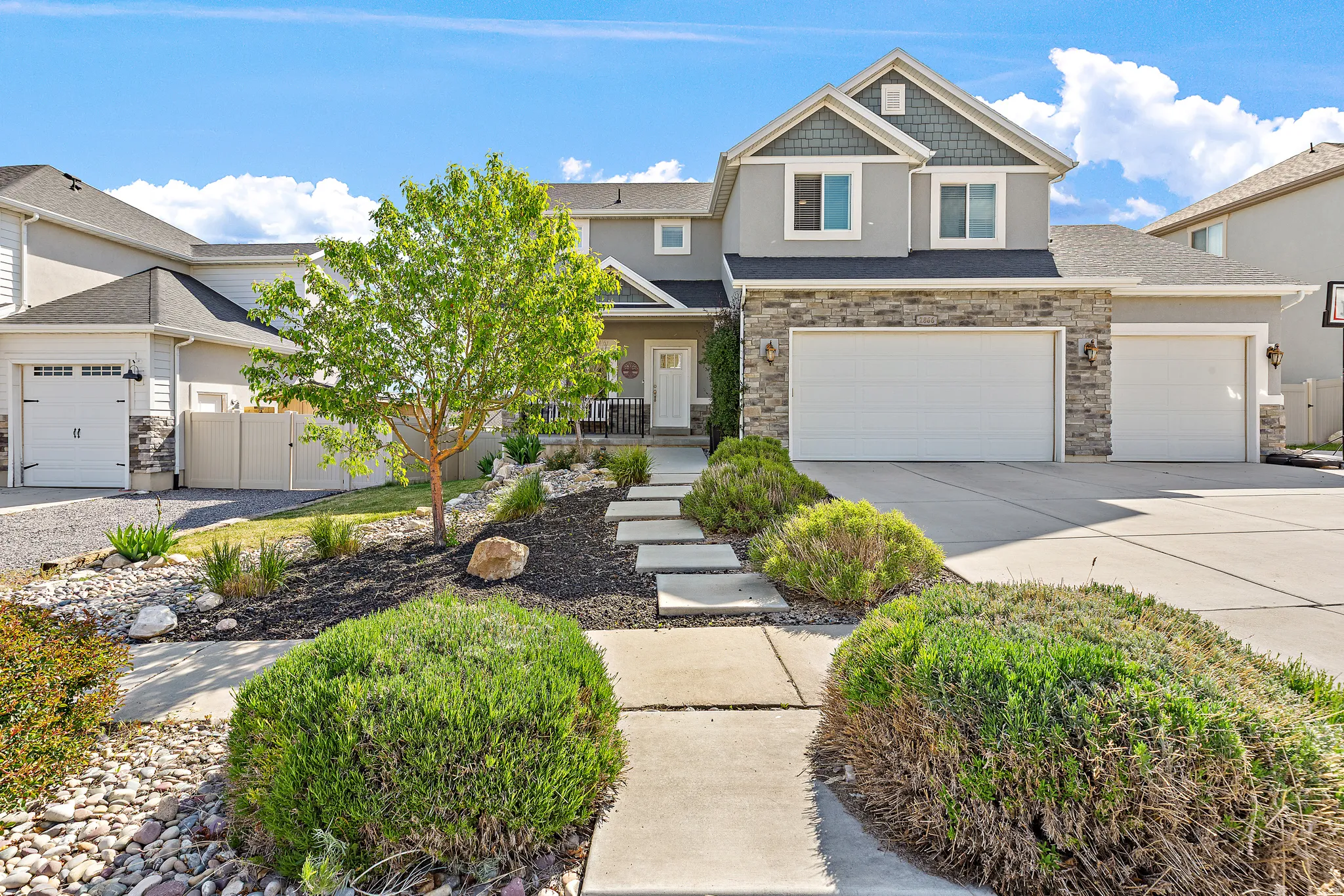 Contemporary residential exterior featuring a stone and siding facade, a two-car garage, and a separate single-car garage