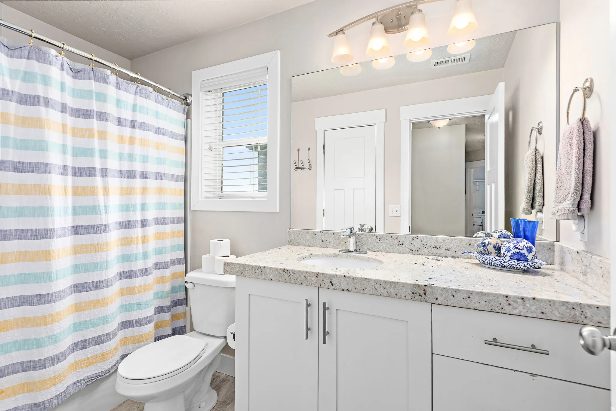 Bathroom featuring a white vanity with a light speckled countertop, under-mount sink, and chrome faucet