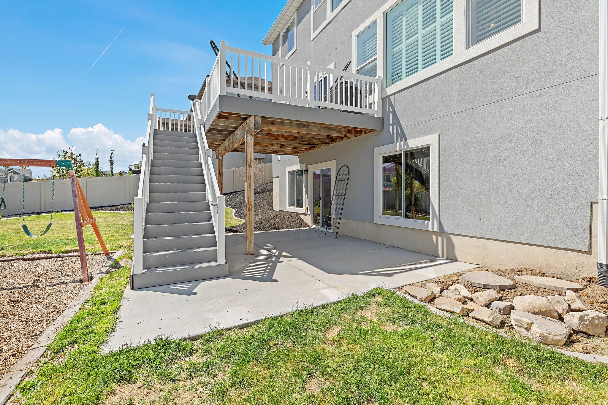 Expansive concrete patio with direct access to an upper-level deck via a staircase