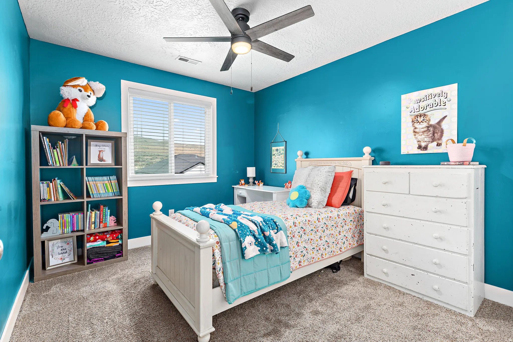 Carpeted room featuring a ceiling fan with integrated lighting, a window with horizontal blinds, and a built-in bookshelf