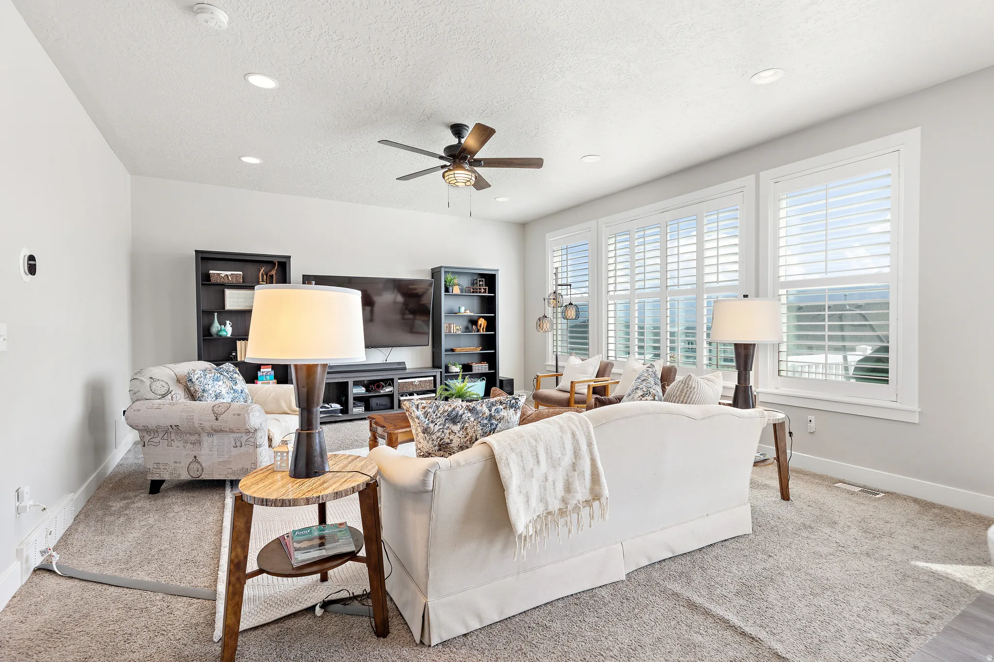 Living area featuring recessed lighting, a ceiling fan, and multiple windows with white plantation shutters