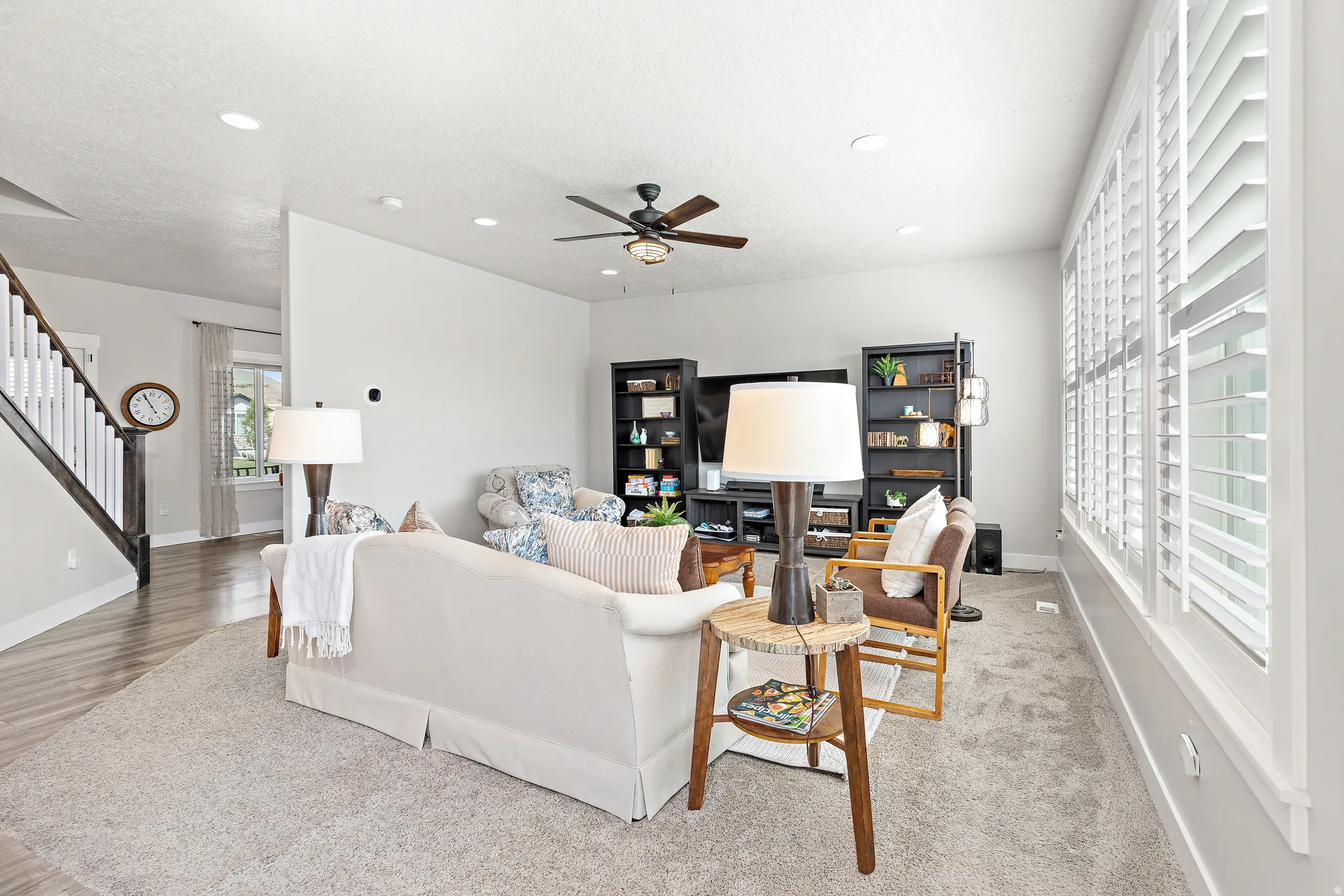 Spacious living area featuring neutral carpeting, recessed lighting, and a ceiling fan