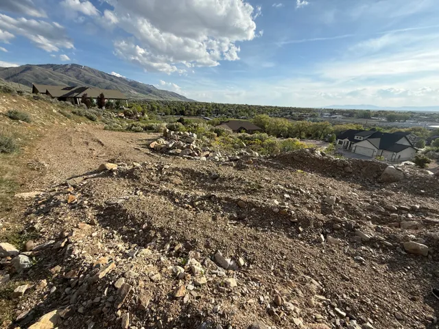 Mountainous terrain featuring a clear sky, distant homes, and visible vegetation