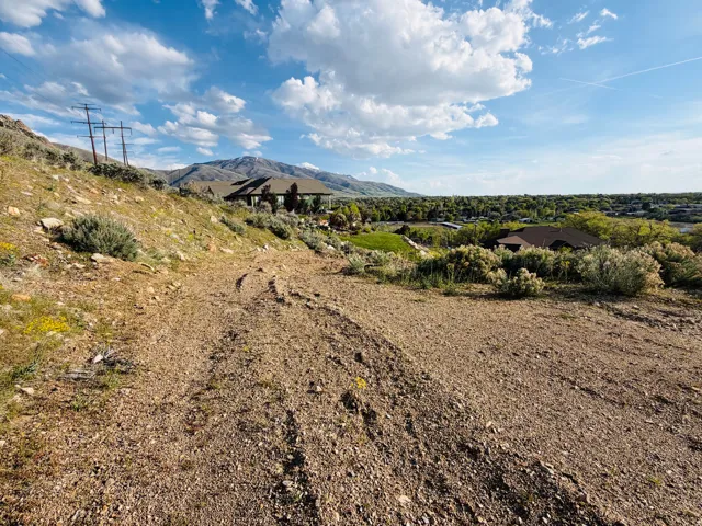 Expansive undeveloped land parcel featuring a gentle slope, gravel terrain, and scattered low-growth vegetation