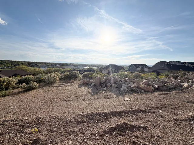 Elevated building site featuring a gravel and dirt surface, natural rock formations, and varied scrub brush