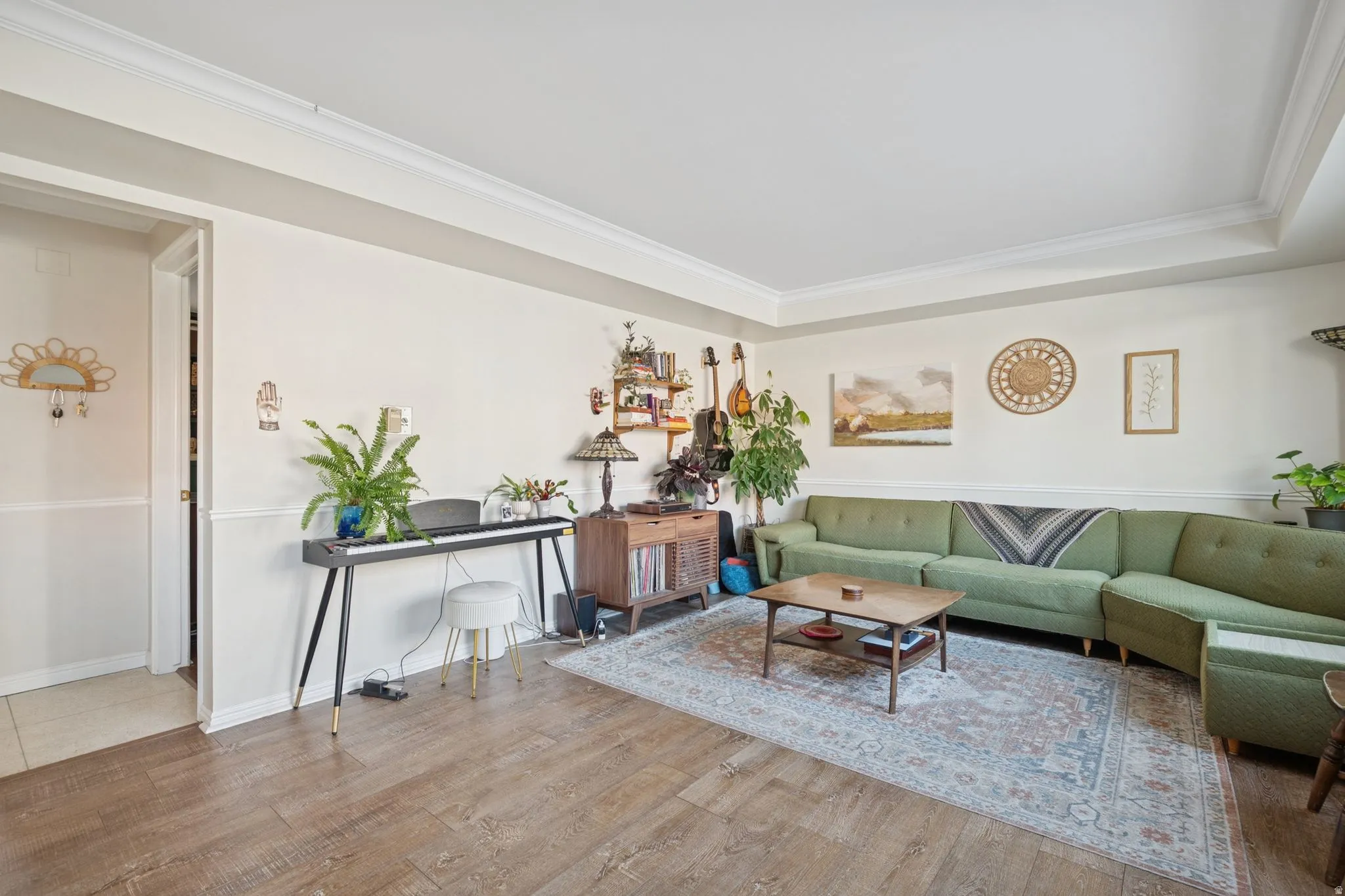 Living room with wood finished floors, crown molding, and a raised ceiling