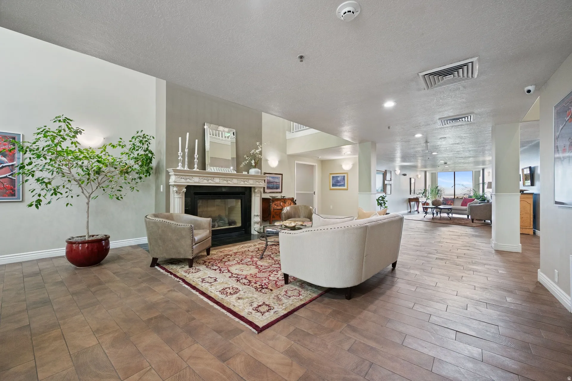 Living area featuring a glass covered fireplace, wood finished floors, a textured ceiling, and recessed lighting