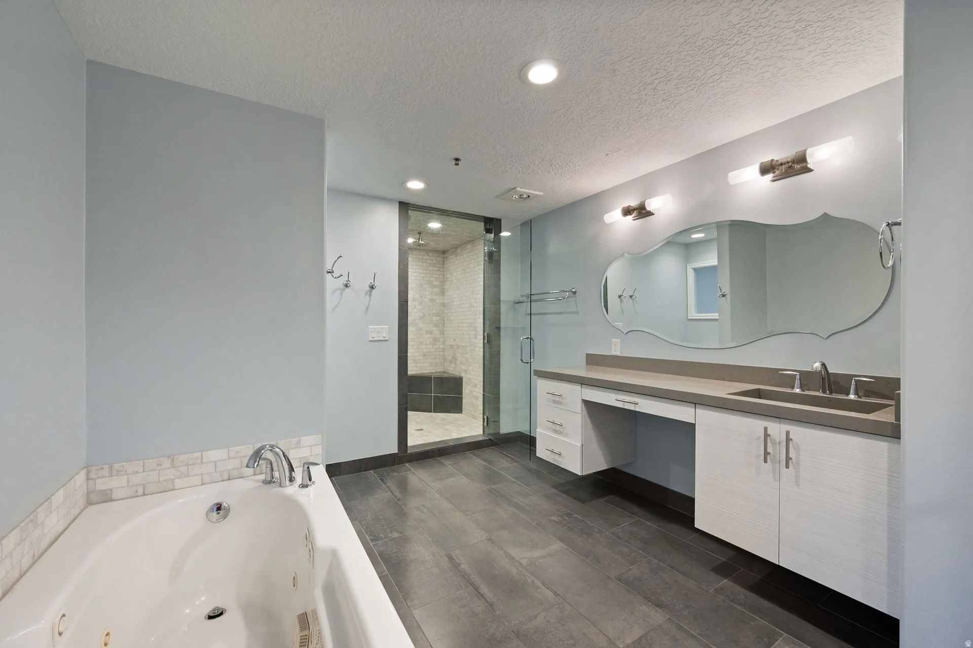 Bathroom featuring vanity, a textured ceiling, recessed lighting, a shower stall, and dark wood-style floors