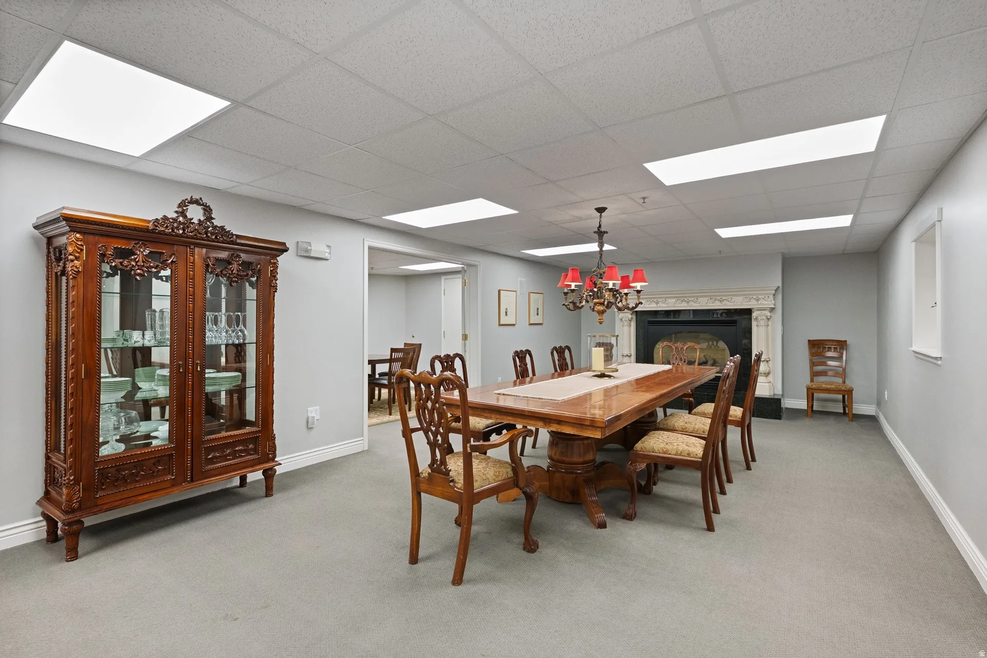 Dining area featuring a paneled ceiling, light colored carpet, and a glass covered fireplace