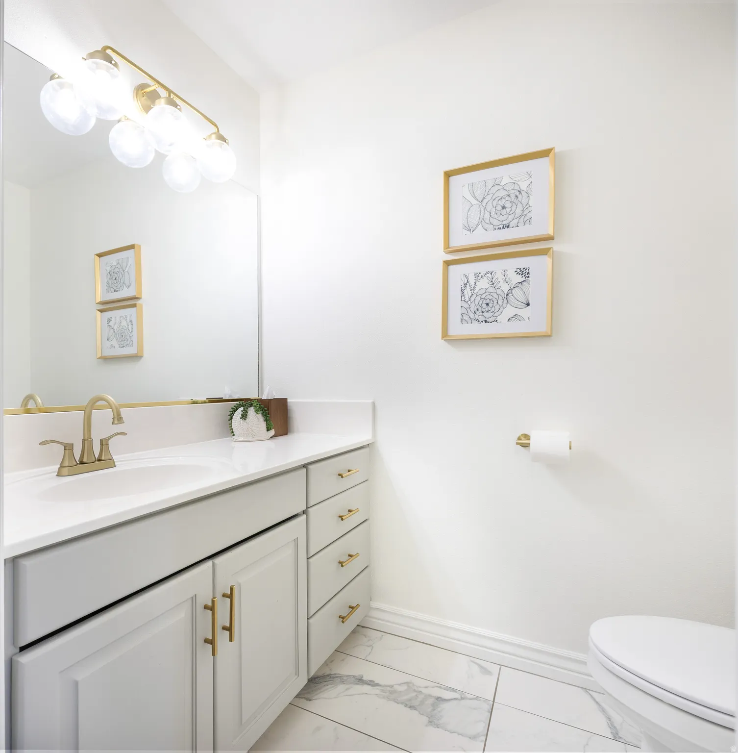 Bathroom featuring a vanity with white cabinetry, gold-tone hardware, and a white countertop
