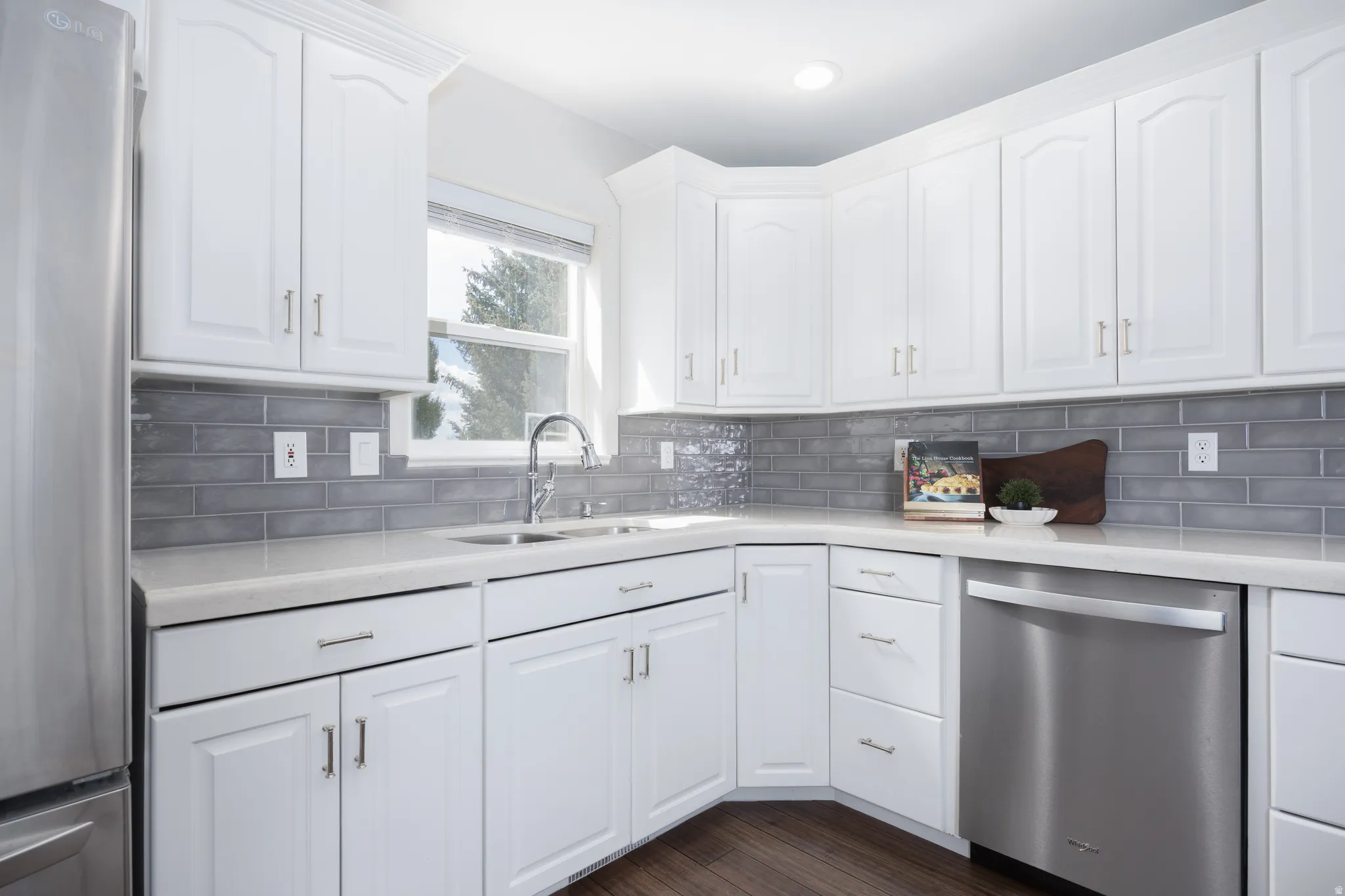 White cabinetry with brushed nickel hardware, light-toned countertops, and a gray subway tile backsplash