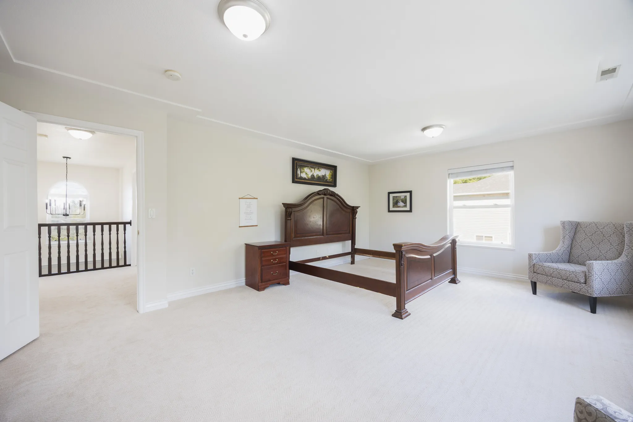 Spacious carpeted room featuring crown molding, a large window with blinds, and flush mount lighting