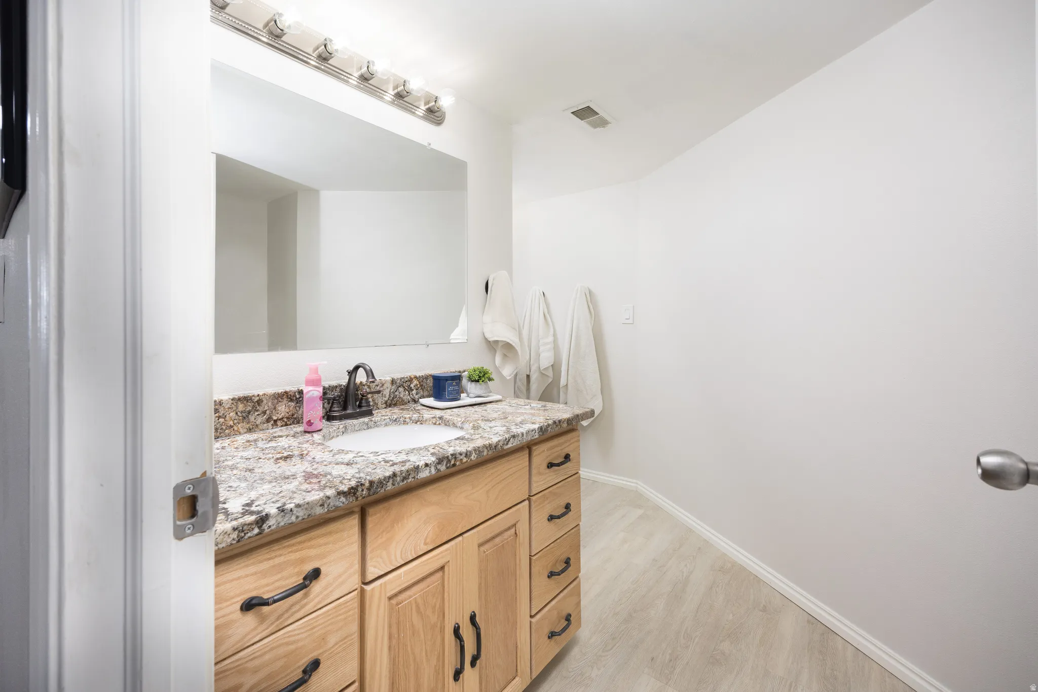 Bathroom featuring a wood-finish vanity with an undermount sink, granite countertop, and oil-rubbed bronze faucet
