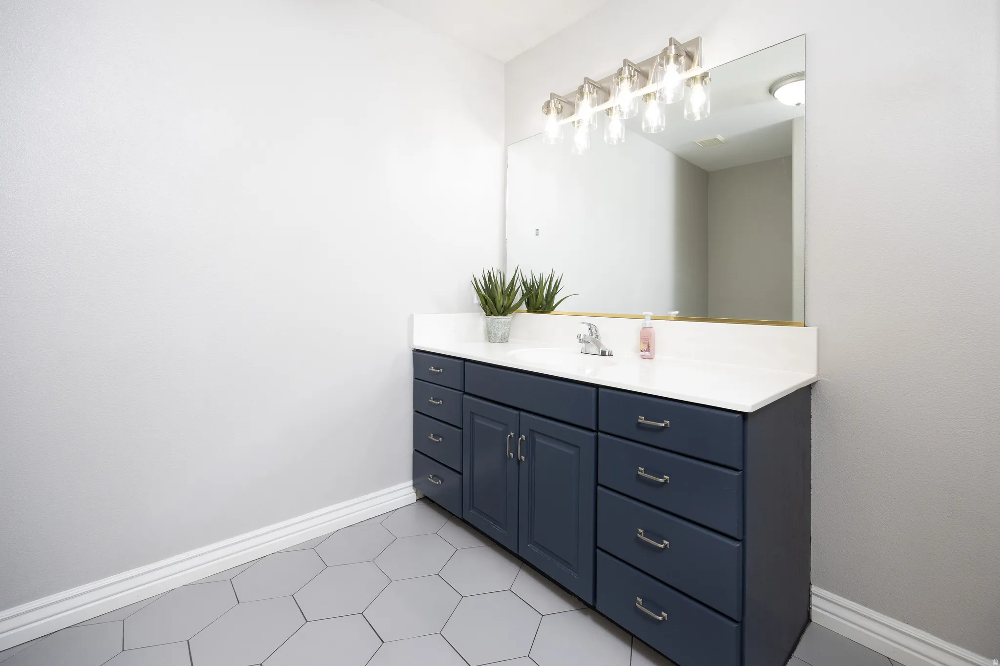 Bathroom featuring a wide vanity with a white countertop, an undermount sink, and a chrome faucet