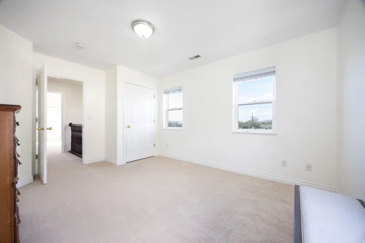 Carpeted room with two double-hung windows, a flush-mount ceiling light, a white paneled door, and white baseboards