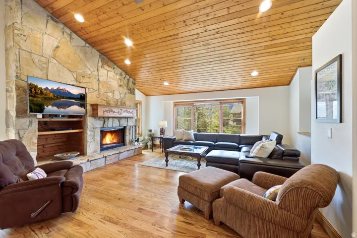 Living room featuring a vaulted wood ceiling, light wood-style flooring, a fireplace, and recessed lighting