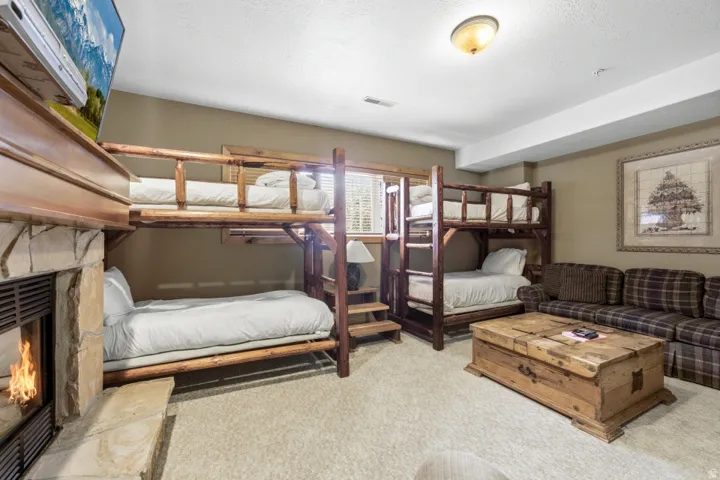 Bedroom featuring a stone fireplace and light colored carpet