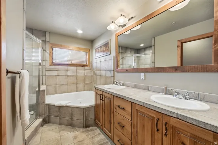 Bathroom with a garden tub, double vanity, a stall shower, and light tile patterned flooring