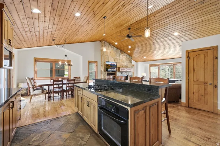 Kitchen featuring a breakfast bar area, pendant lighting, black appliances, a kitchen island, and a fireplace