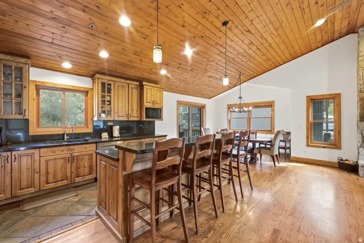 Kitchen featuring a breakfast bar, wood finish cabinetry, a center island, decorative backsplash, and a vaulted wood ceiling