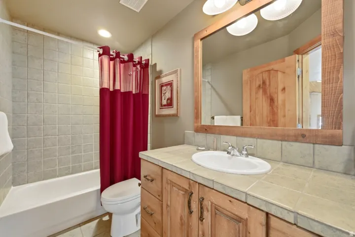 Bathroom with vanity, shower / bathtub combination with curtain, recessed lighting, and light tile patterned floors