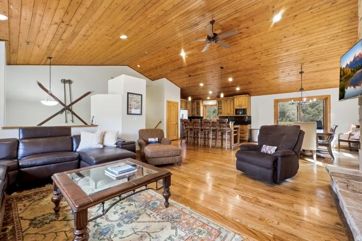 Living area featuring a vaulted wood ceiling, a chandelier, ceiling fan, and light wood-style flooring