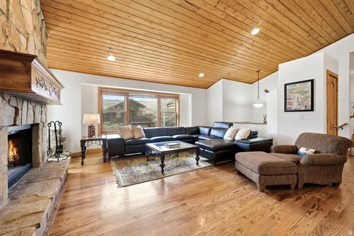 Living area with light wood-style flooring, a vaulted wood ceiling, a stone fireplace, and recessed lighting