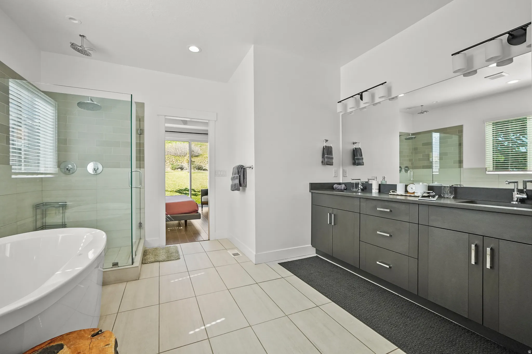 Full bathroom featuring a stall shower, double vanity, light tile patterned flooring, a freestanding tub, and recessed lighting