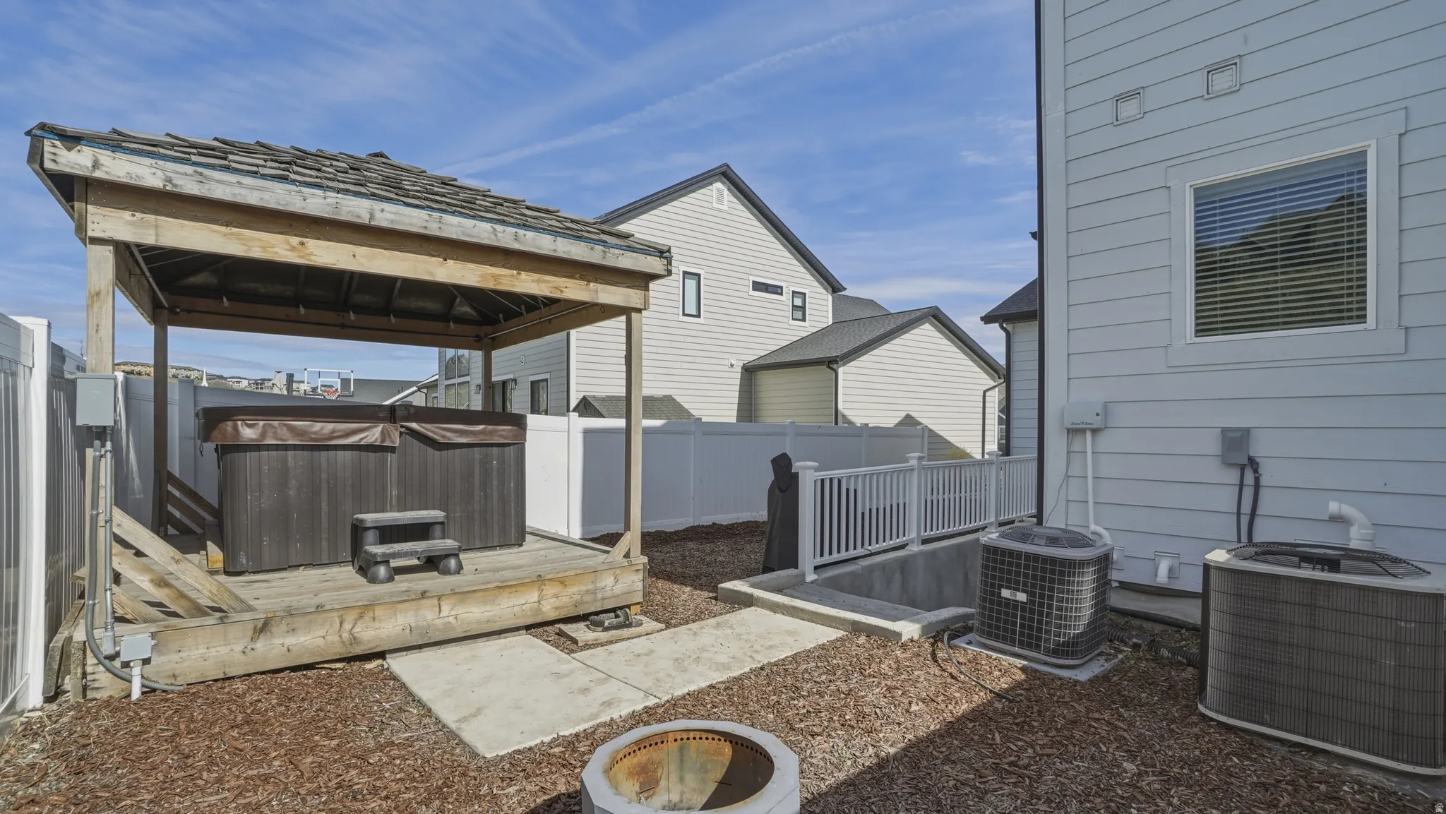 Fenced backyard with a wooden deck, a gazebo, and a hot tub