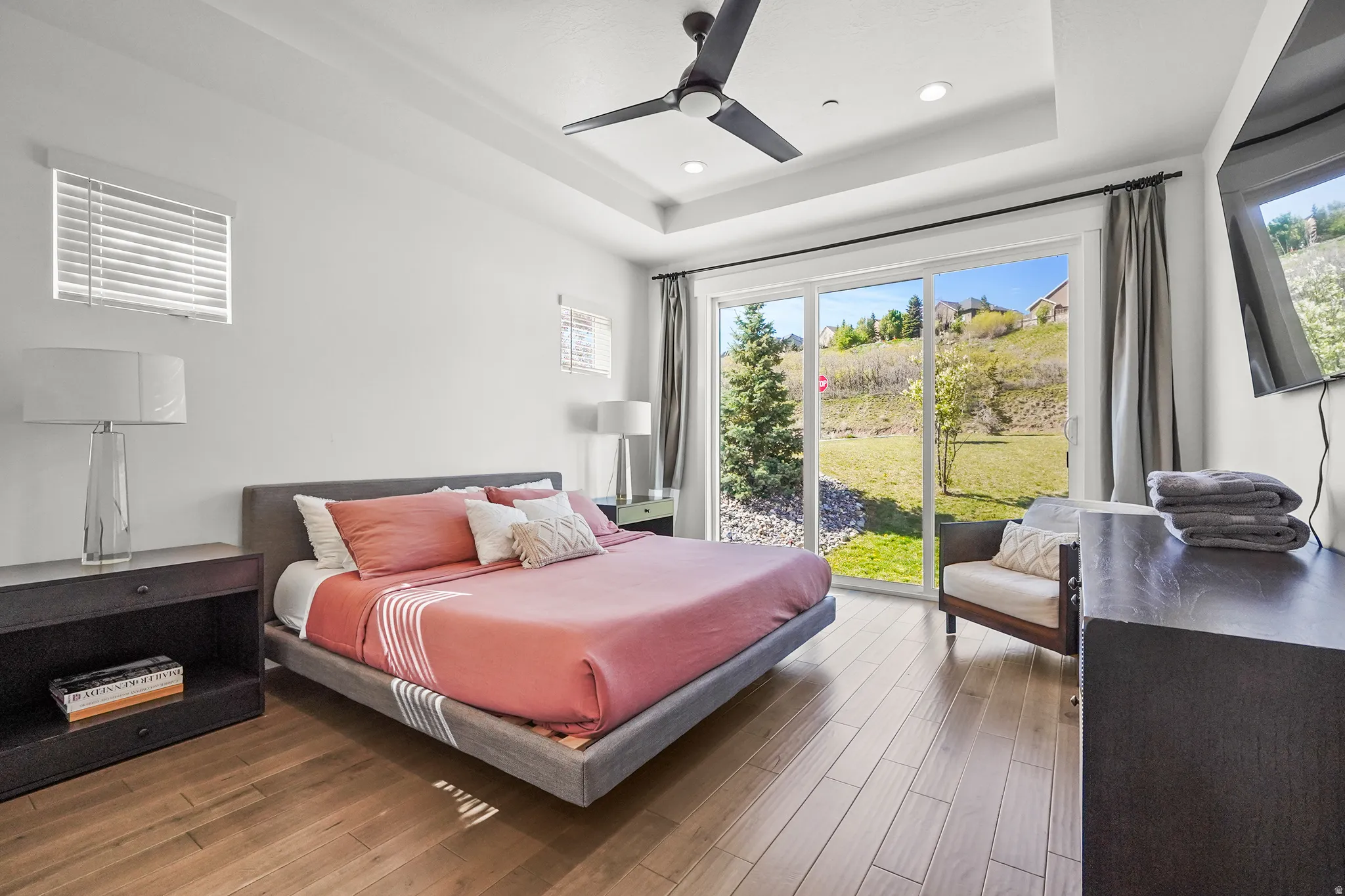 Bedroom with dark wood-type flooring, a tray ceiling, ceiling fan, and recessed lighting