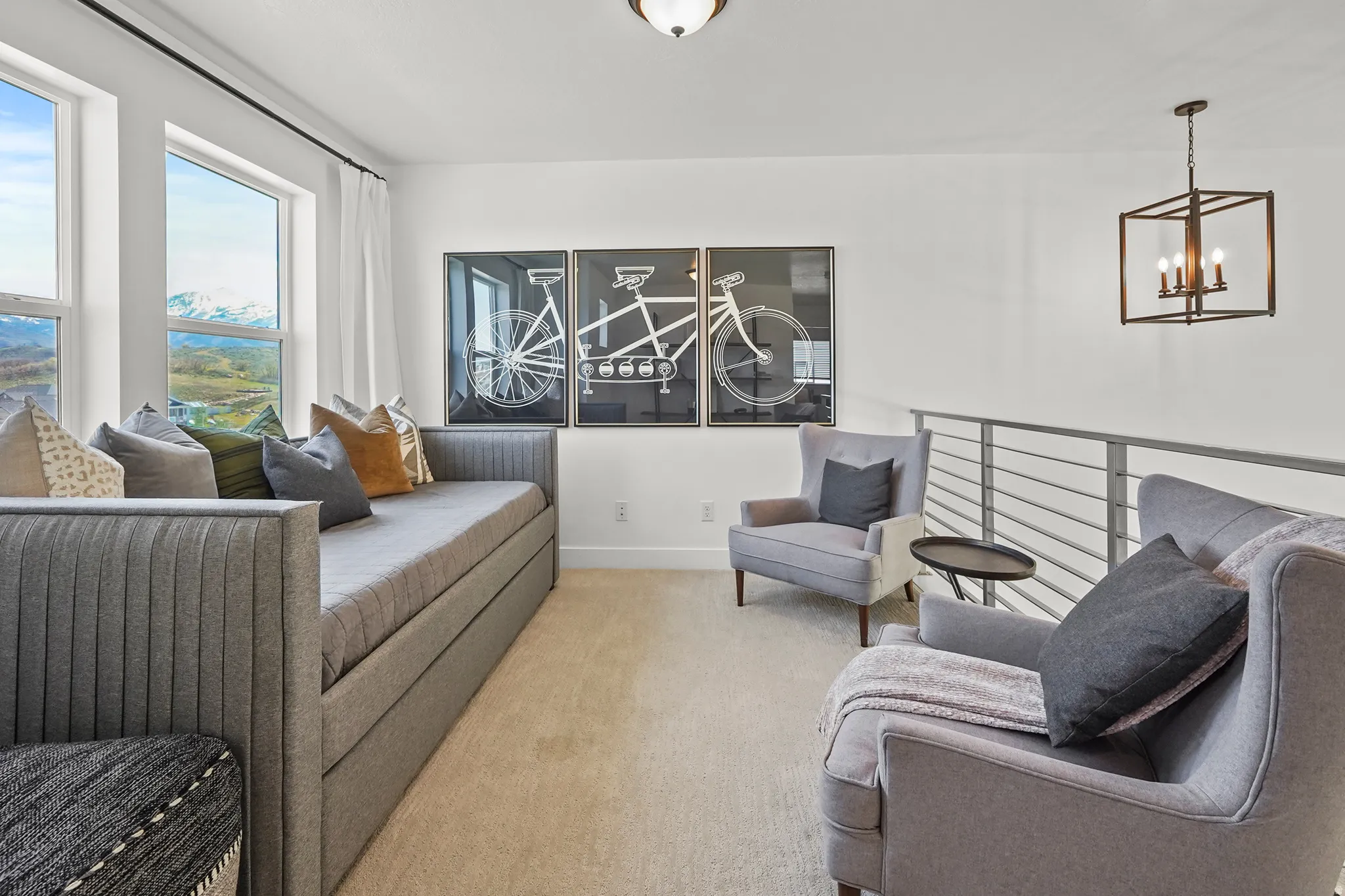 Living area with light colored carpet and suspended lighting