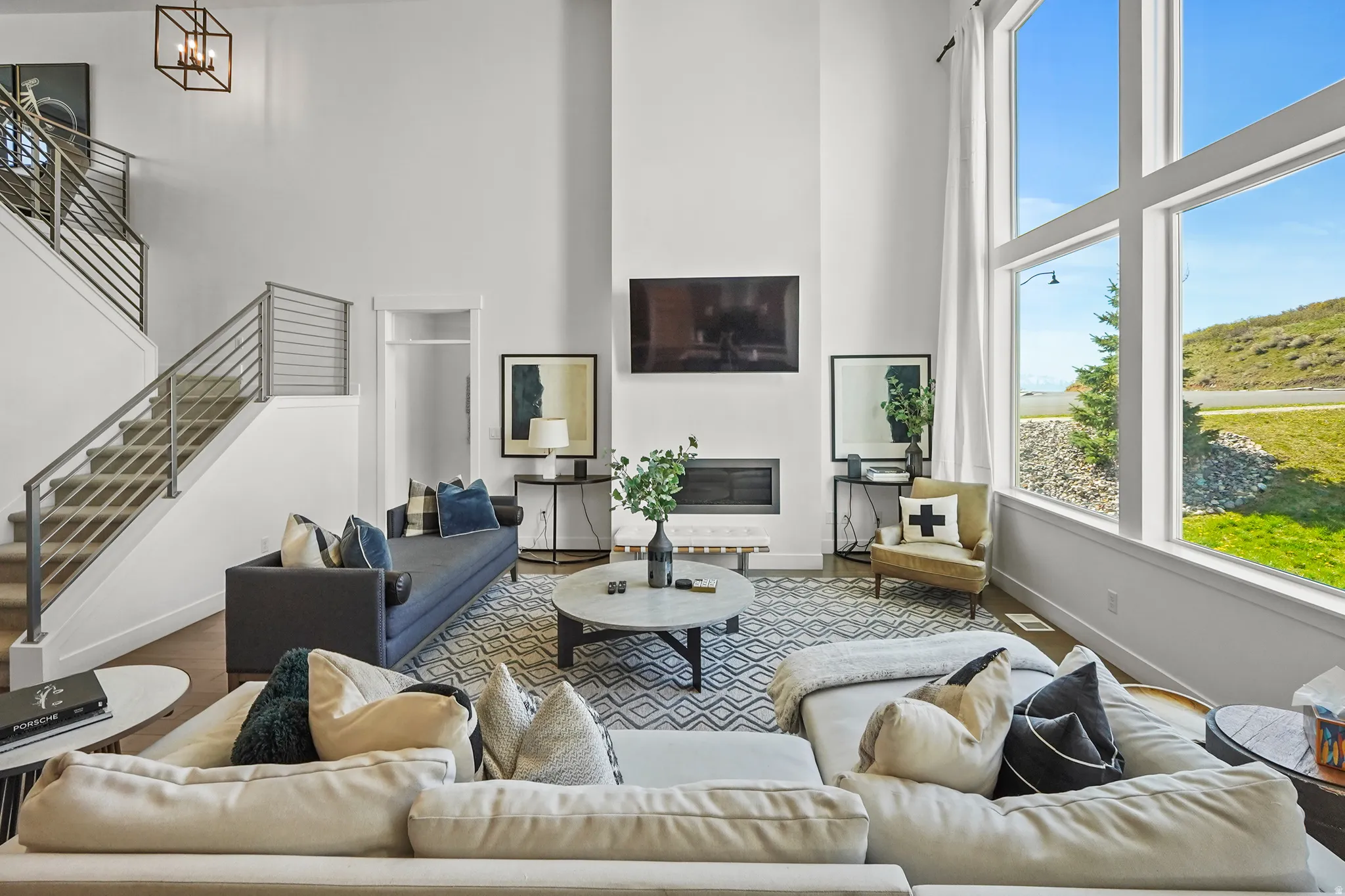 Living area featuring a high ceiling, wood finished floors, and a glass covered fireplace