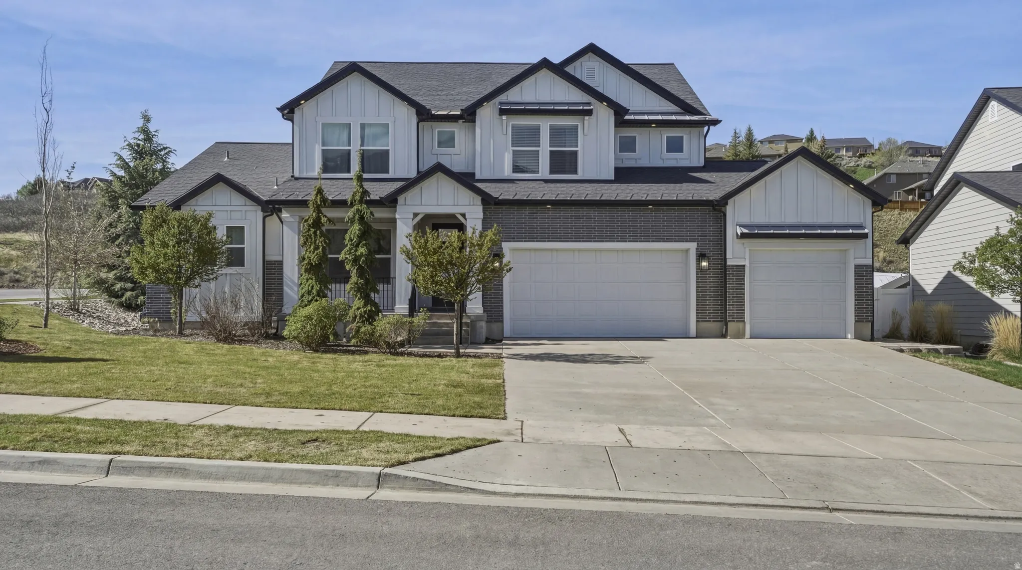 Craftsman-style home featuring board and batten siding, driveway, a shingled roof, and brick siding
