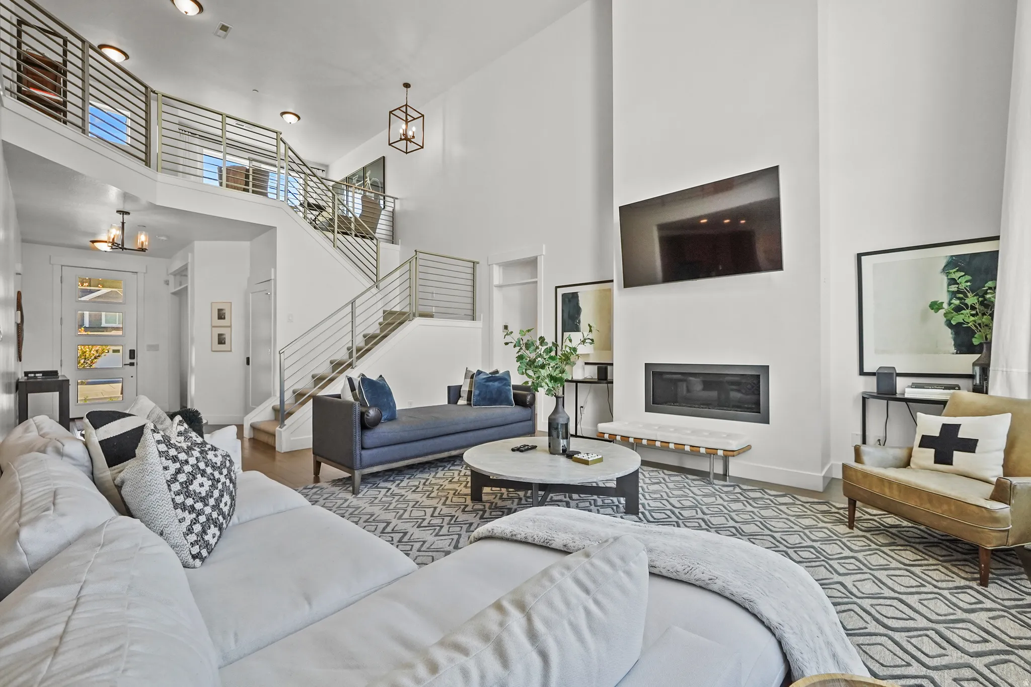 Living room featuring suspended lighting, a glass covered fireplace, and a high ceiling