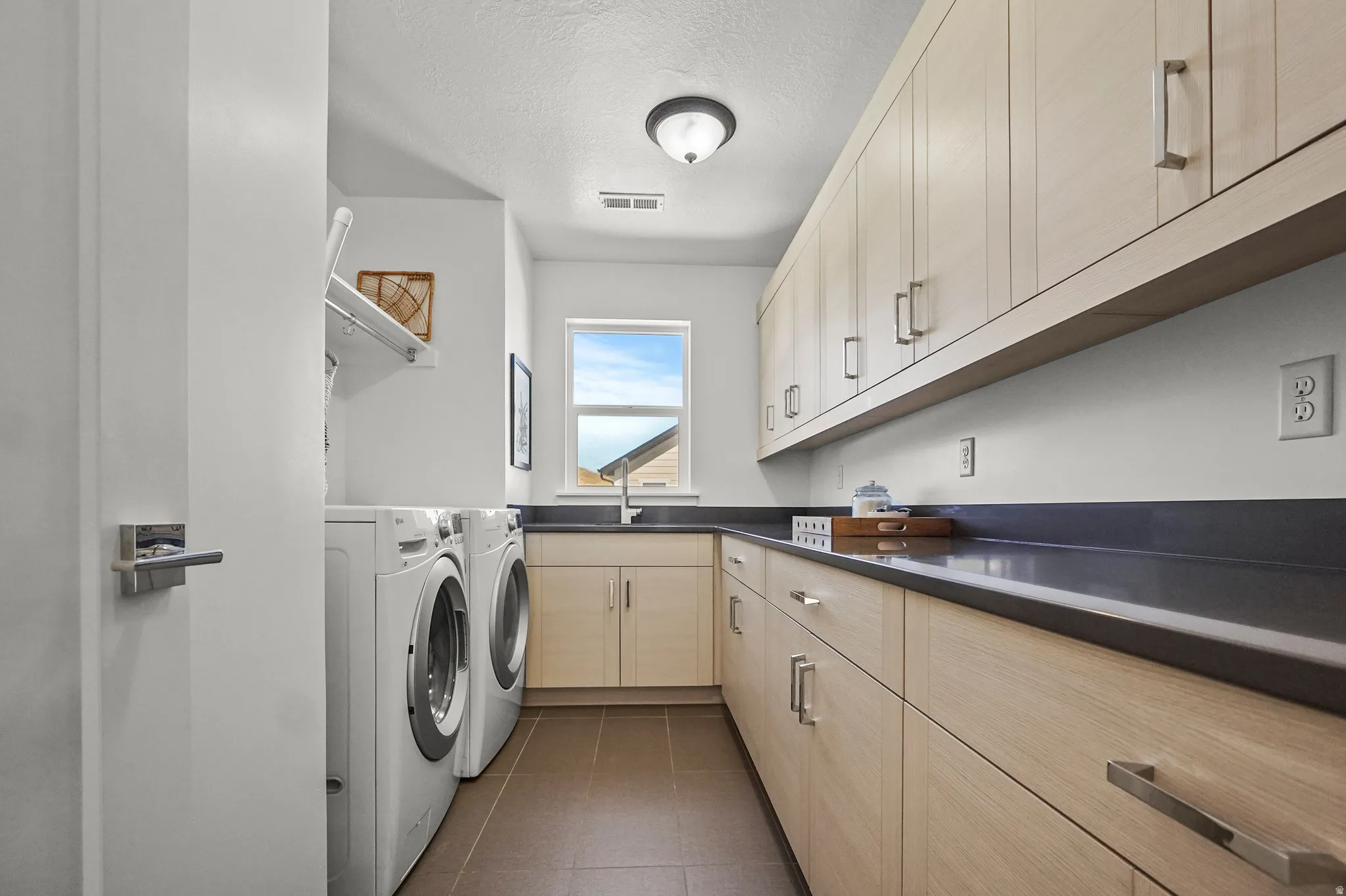 Laundry room featuring cabinet space, separate washer and dryer, a textured ceiling, and dark tile patterned floors