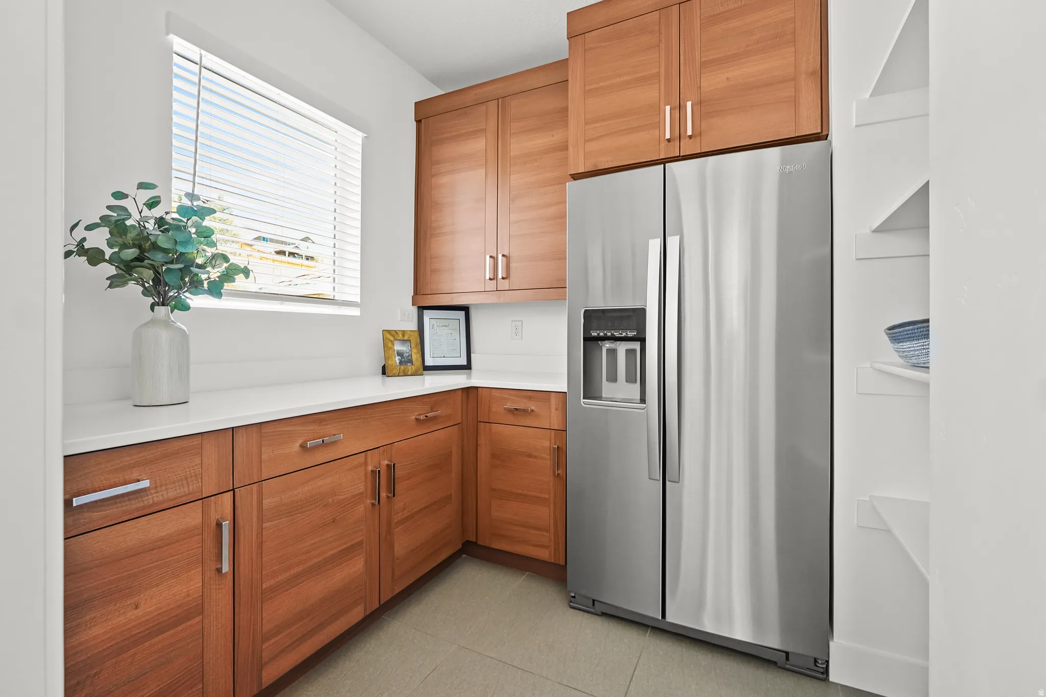 Kitchen with stainless steel refrigerator with ice dispenser, wood finish cabinets, and light stone countertops