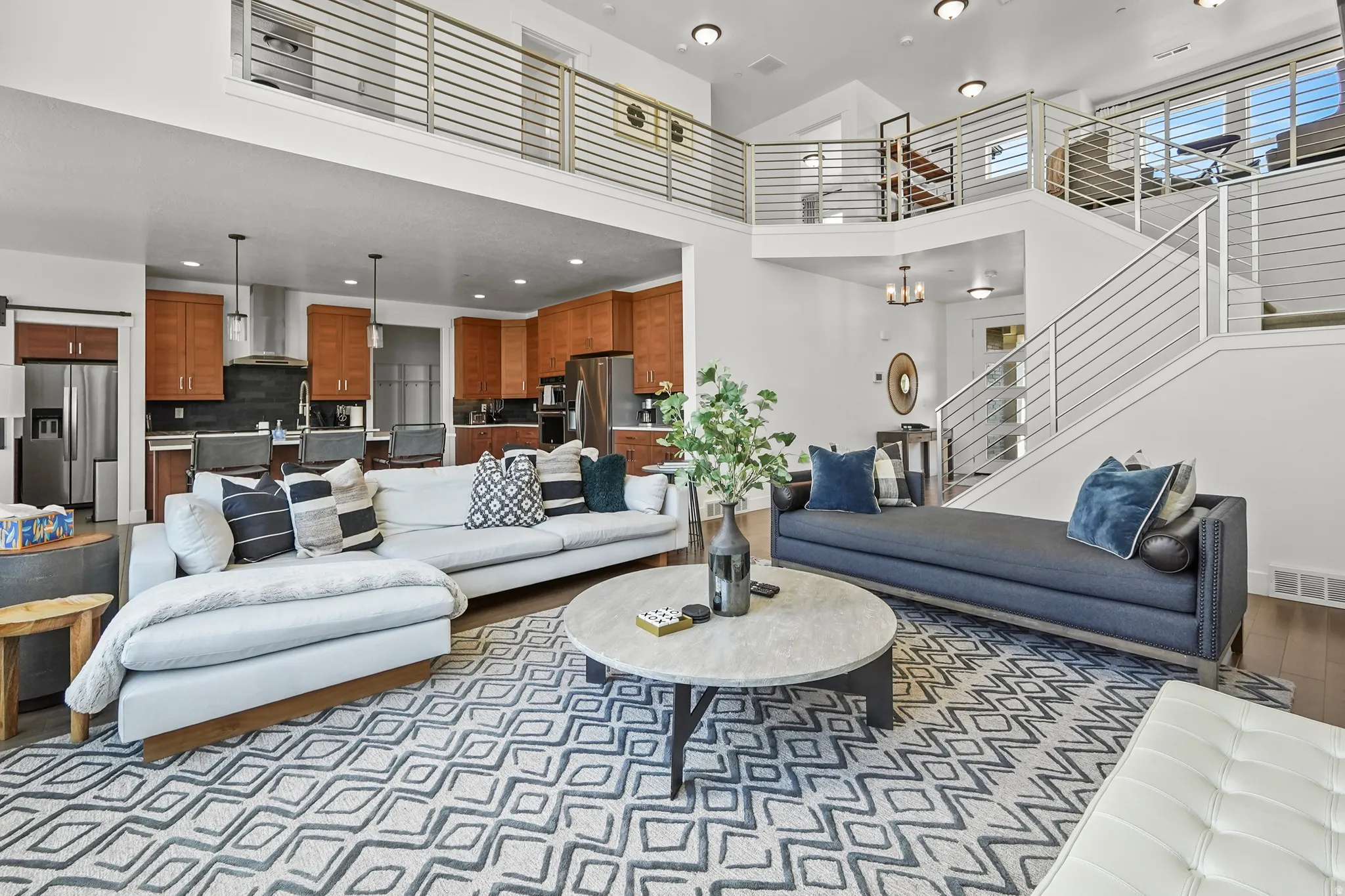 Living room with suspended lighting, a high ceiling, and light wood-style floors