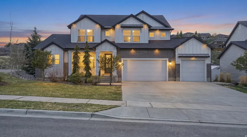 Modern farmhouse style home featuring board and batten siding, driveway, brick siding, and a front yard