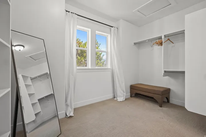 Walk in closet with attic access and light colored carpet